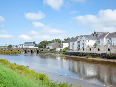 a river in a town with a bridge and buildings at 6 Camelside in Wadebridge