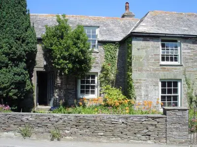 an old stone house with a stone wall and flowers at 4 Bed in Tintagel oc-tolbo in Tintagel