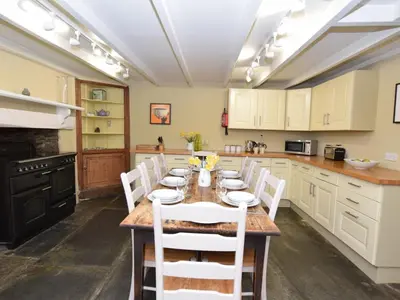 a kitchen with a wooden table and white chairs at 4 Bed in Tintagel oc-tolbo in Tintagel