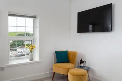 a living room with a chair and a window at Chy Lowen in Helston