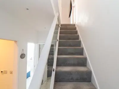 a staircase in a house with white walls and gray stairs at Chy Lowen in Helston