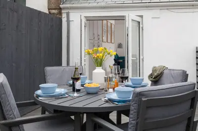 a table with chairs and a bottle of wine at Chy Lowen in Helston