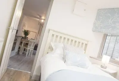 a bedroom with a white bed and a table at Stunning cosy cottage in old town Padstow sleeps 4 in Padstow