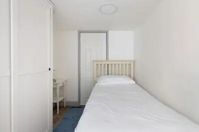 a white bedroom with a bed and a desk at Stunning cosy cottage in old town Padstow sleeps 4 in Padstow
