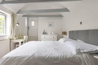 a white bedroom with a large white bed and a desk at Stunning cosy cottage in old town Padstow sleeps 4 in Padstow
