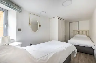 a white bedroom with two beds and a mirror at Stunning cosy cottage in old town Padstow sleeps 4 in Padstow