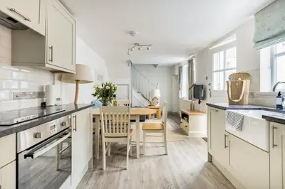 a kitchen with white cabinets and a table and chairs at Stunning cosy cottage in old town Padstow sleeps 4 in Padstow