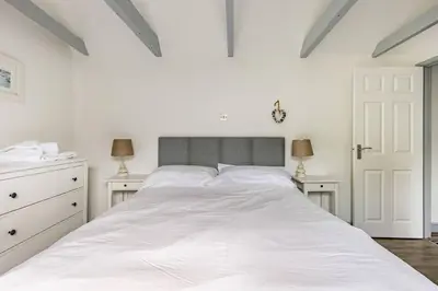 a white bedroom with a large white bed and two lamps at Stunning cosy cottage in old town Padstow sleeps 4 in Padstow