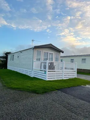 a white house with a fence in the grass at Two bedroom Holiday home in Newquay