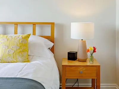 a bed with a lamp and a vase of flowers on a table at 3 Bed in Truro oc-81488 in Saint Just in Roseland