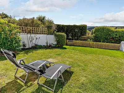 a lawn chair sitting in the grass in a yard at 3 Bed in Truro oc-81488 in Saint Just in Roseland