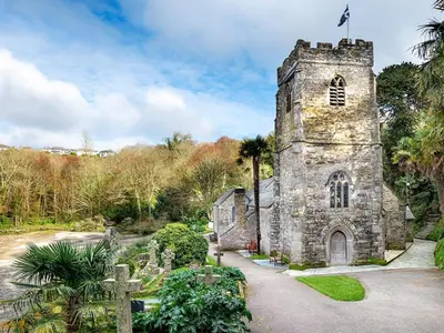an old stone church with a cross in front of it at 3 Bed in Truro oc-81488 in Saint Just in Roseland