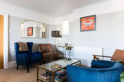 a living room with blue chairs and a table at Tre Lowen in Port Isaac