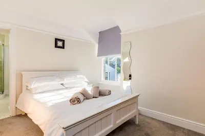 a white bedroom with a bed with a window at Tre Lowen in Port Isaac