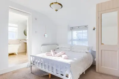 a white bedroom with a crib with pink dolls on it at Tre Lowen in Port Isaac
