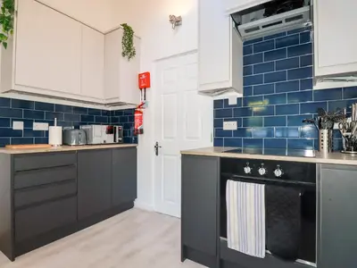 a kitchen with black appliances and blue tiles at Little Seacroft in Newquay