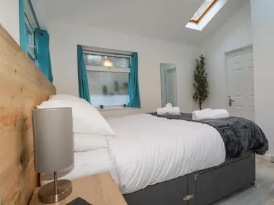 a bedroom with a large bed with white sheets and a window at Little Seacroft in Newquay