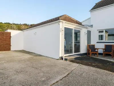 a white garage with two chairs in a driveway at Little Seacroft in Newquay