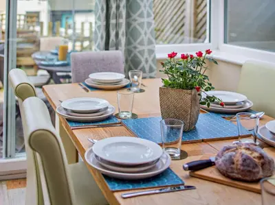 a wooden table with plates and dishes on it at 3 Bed in Truro oc-78090 in Porthtowan