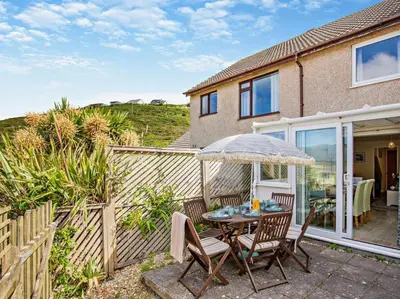 a patio with a table and chairs and an umbrella at 3 Bed in Truro oc-78090 in Porthtowan