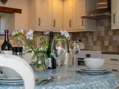 a table with two wine glasses and flowers on it at 2 Bed in Camelford oc-81245 in Camelford