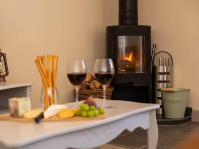 a table with two glasses of wine and a fireplace at 2 Bed in Camelford oc-81245 in Camelford