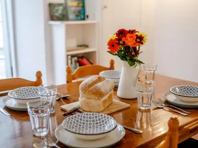 a wooden table with plates and a vase of flowers at 2 Bed in Fowey oc-76624 in Fowey