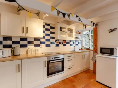 a kitchen with white cabinets and blue and white tiles at 2 Bed in Fowey oc-76624 in Fowey