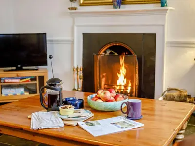 a table with a bowl of fruit in front of a fireplace at 2 Bed in Fowey oc-76624 in Fowey