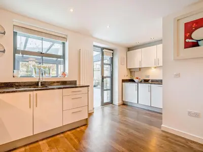a kitchen with white cabinets and a wooden floor at 4 Bed in St. Austell oc-41199 in Charlestown