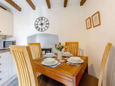 a dining room table with chairs and a clock on the wall at 2 Bed in Launceston oc-85912 in Trewen