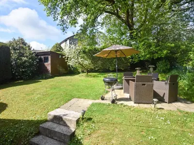 a grill with chairs and an umbrella in a yard at 2 Bed in Launceston oc-85912 in Trewen