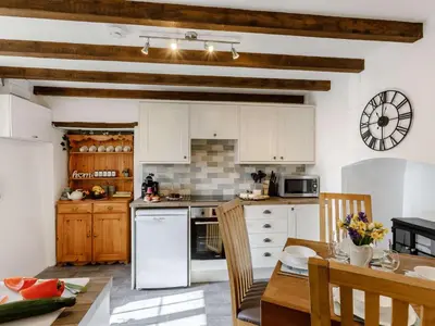 a kitchen with white cabinets and a table with chairs at 2 Bed in Launceston oc-85912 in Trewen