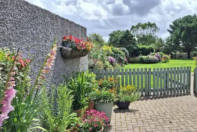 a garden with flowers in pots on a fence at Rural Cornish Cottage in Truro