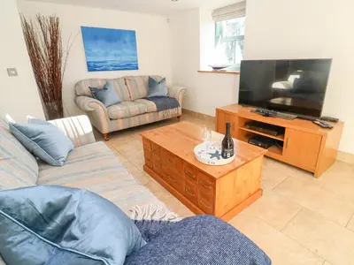 a living room with a couch and a flat screen tv at 5 The Old Smokehouse in St Austell