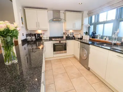a kitchen with white cabinets and a vase of flowers at 5 The Old Smokehouse in St Austell