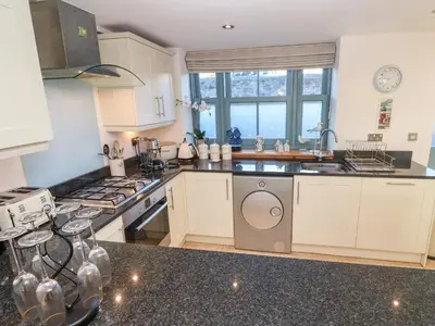 a kitchen with white cabinets and a sink and a dishwasher at 5 The Old Smokehouse in St Austell