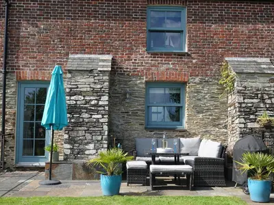 a patio with a table and an umbrella at 5 The Old Smokehouse in St Austell