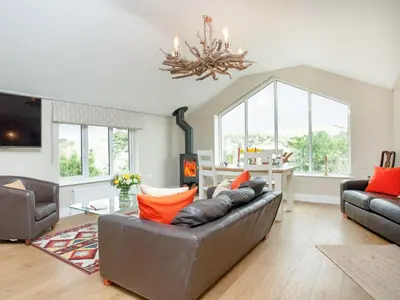 a living room with a couch and a chandelier at Meadowside in Saint Mawes
