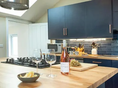 a bottle of wine and two wine glasses on a kitchen counter at Meadowside in Saint Mawes
