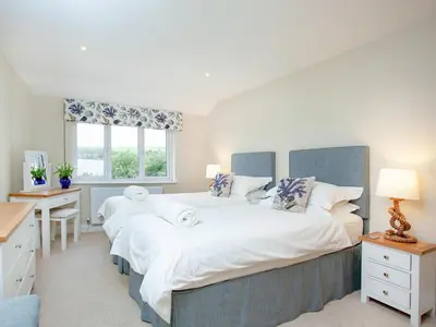 two beds in a bedroom with a desk and a window at Meadowside in Saint Mawes