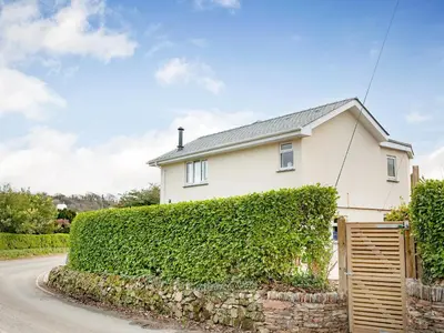 a white house with a hedge in front of a road at Meadowside in Saint Mawes