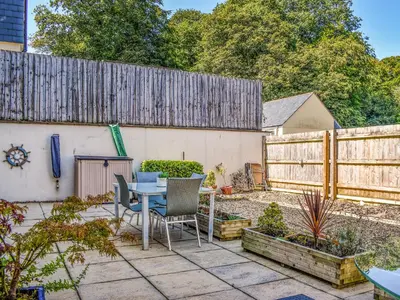 a patio with a table and chairs and a fence at The Beach Retreat in Porth