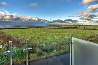 a view of a field from a glass door at Finest Retreats - Treknow Summerhut in Tintagel