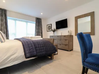 a bedroom with a bed and a mirror and a chair at 31 Cliff Edge in Newquay