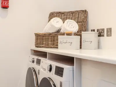 a laundry room with a washing machine and baskets on a shelf at 31 Cliff Edge in Newquay