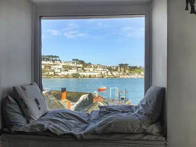 a window with a bed looking out at the water at The Lookout in Polruan