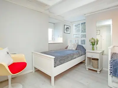 a white bedroom with a bed and a chair at The Lookout in Polruan