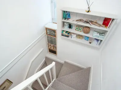 a stairwell with white walls and white shelves at The Lookout in Polruan