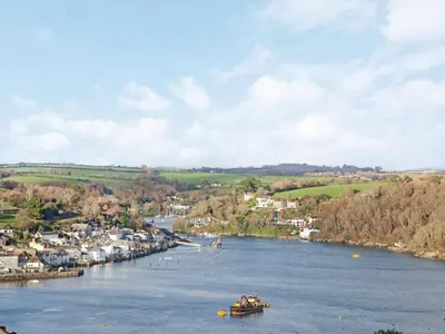 a boat on a river with a town in the background at The Lookout in Polruan